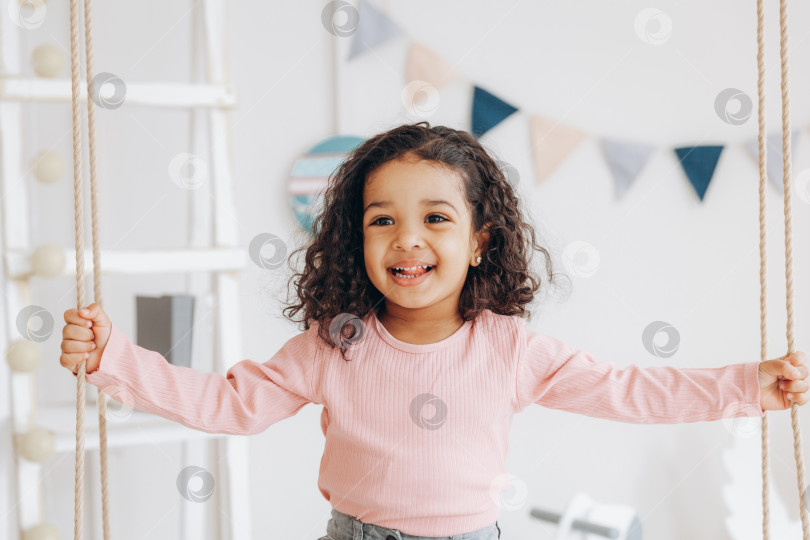Скачать маленькая темнокожая девочка катается на качелях. дизайн интерьера детской комнаты фотосток Ozero