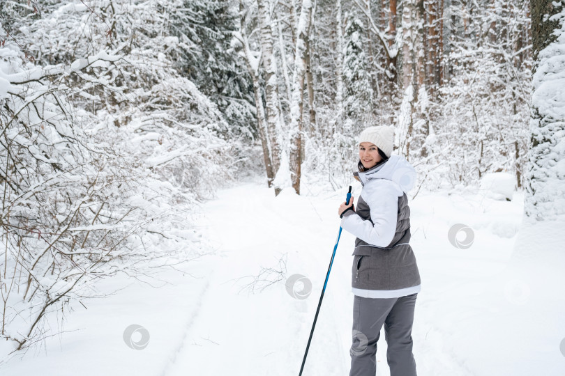 Скачать Лыжница женщина в мембранной куртке с лыжными палками в руках спиной на фоне заснеженного леса. Катание на беговых лыжах в зимнем лесу, спорт на открытом воздухе, здоровый образ жизни. фотосток Ozero