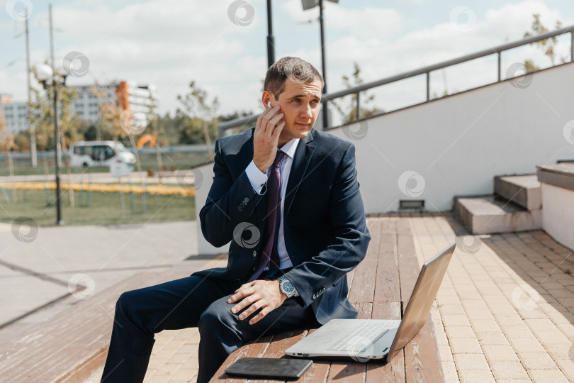 Скачать Мужчина в деловом костюме и с ноутбуком сидит на скамейке. бизнесмен с ноутбуком. фотосток Ozero