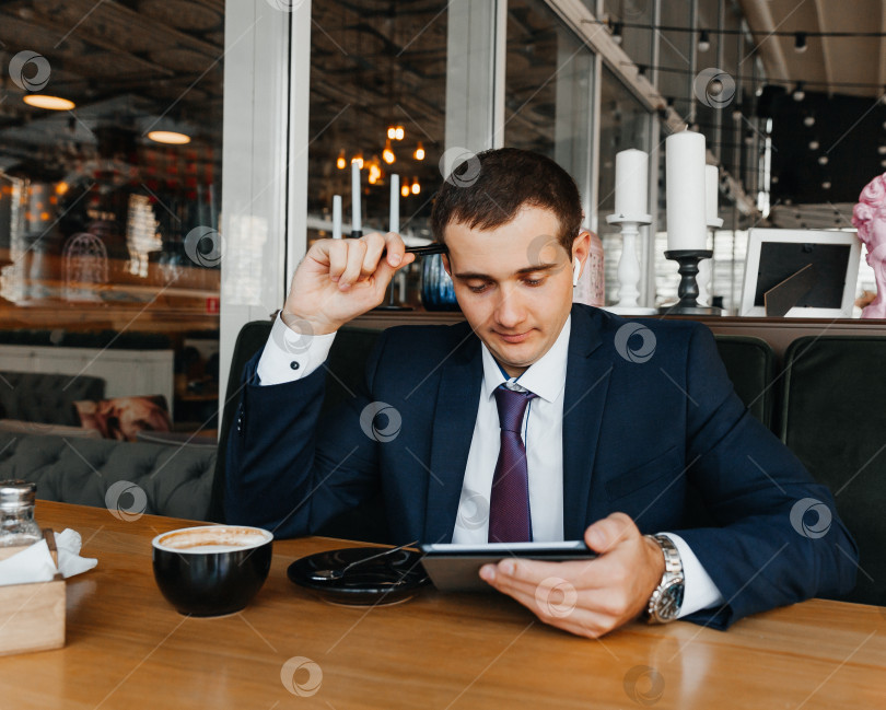 Скачать Красивый молодой бизнесмен улыбается и пьет кофе в кафе. мужчина в костюме с чашкой кофе. фотосток Ozero