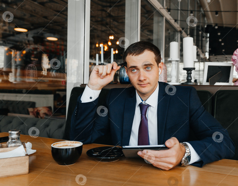 Скачать Красивый молодой бизнесмен улыбается и пьет кофе в кафе. мужчина в костюме с чашкой кофе. фотосток Ozero