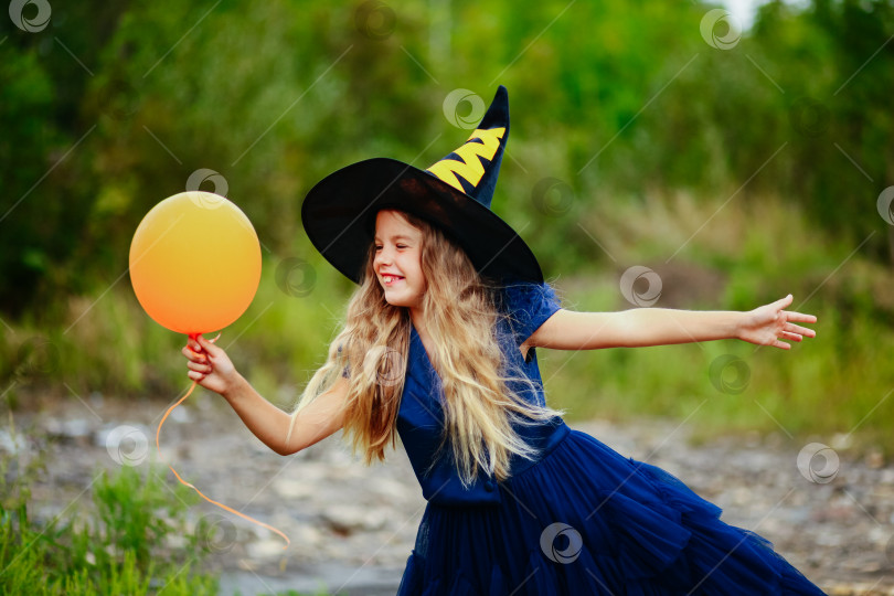 Скачать маленькая девочка в костюме ведьмы с оранжевым мячом на улице. Хэллоуин. фотосток Ozero