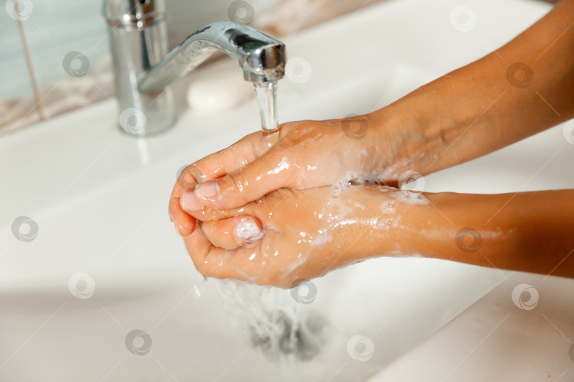 Скачать Мойте руки с мылом под проточной водой из-под крана. женские руки под струей воды. фотосток Ozero