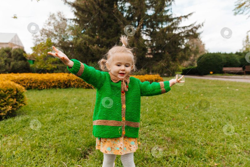 Скачать портрет счастливой маленькой девочки в осенней одежде. ребенок смеется на фоне природы. фотосток Ozero