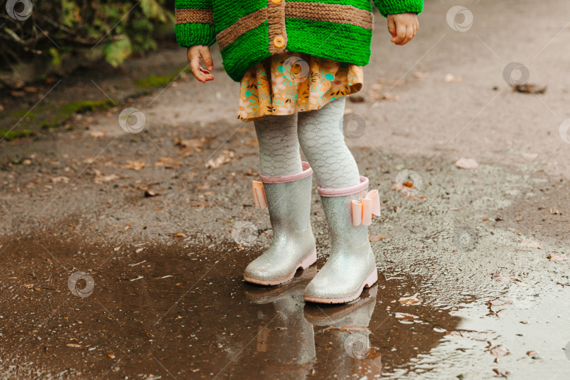 Скачать детские ножки в резиновых сапожках крупным планом. ребенок бежит по лужам осенним днем. фотосток Ozero