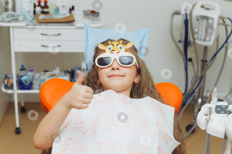 Скачать стоматолог проводит процедуру обследования милой маленькой девочки. Маленькая девочка сидит в кабинете дантиста фотосток Ozero