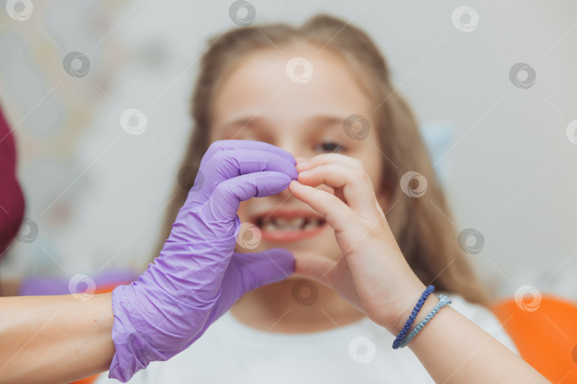 Скачать Избирательный фокус рук стоматолога и маленькой девочки-пациентки в форме сердца фотосток Ozero