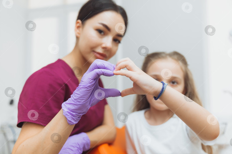 Скачать Избирательный фокус рук стоматолога и маленькой девочки-пациентки в форме сердца фотосток Ozero