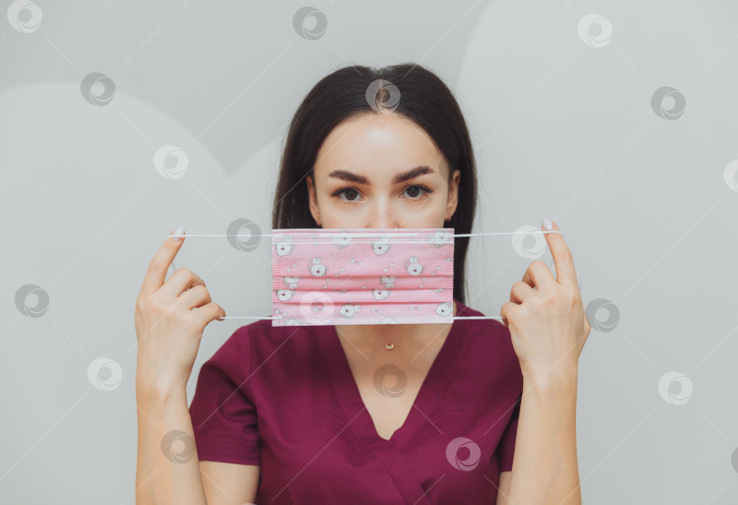 Скачать Девушка-врач прижимает к лицу розовую маску. Инструкции по ношению маски для лица фотосток Ozero
