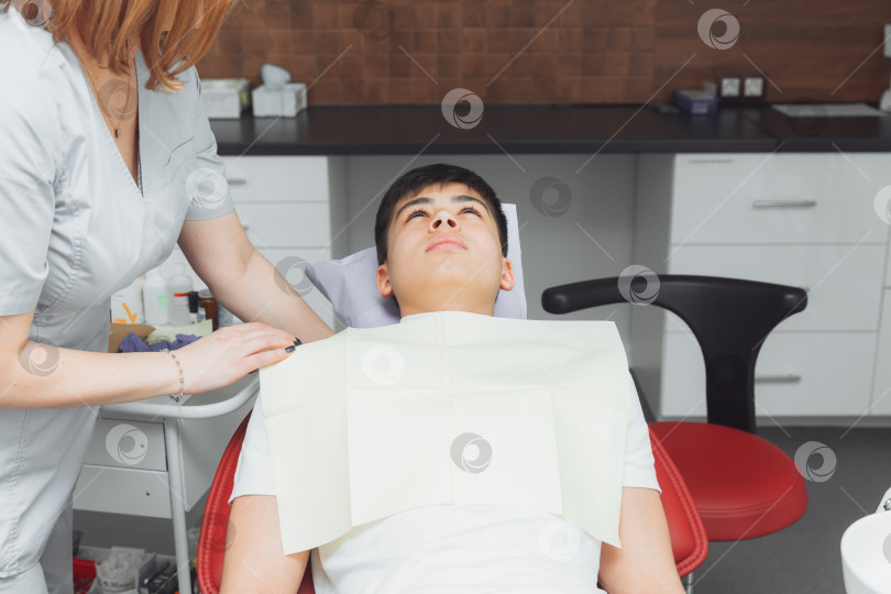 Скачать стоматолог накладывает на пациента зубную салфетку. Подготовка пациента к стоматологическому осмотру фотосток Ozero