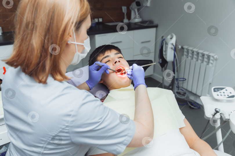 Скачать Стоматолог осматривает зубы мальчика 13 лет в клинике. детская стоматология фотосток Ozero