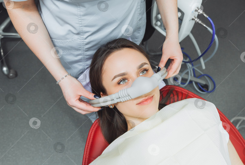 Скачать стоматолог надевает на своего пациента ингаляционную седативную маску. фотосток Ozero