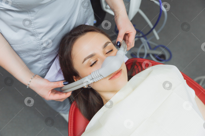 Скачать стоматолог надевает на своего пациента ингаляционную седативную маску. фотосток Ozero