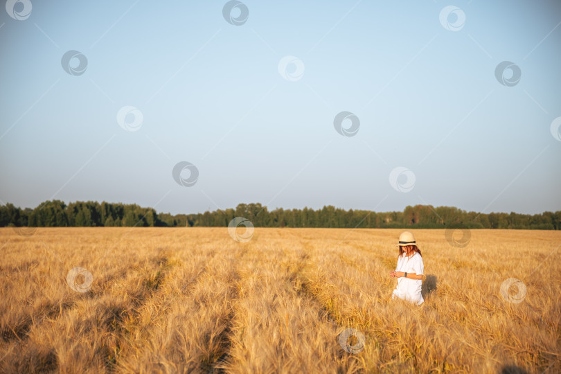 Скачать Девушка в шляпе идет по пшеничному полю на закате фотосток Ozero