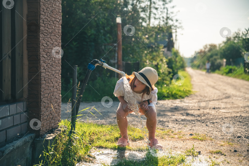 Скачать Симпатичная девушка в деревне пьет воду из-под крана, деревенская жизнь фотосток Ozero