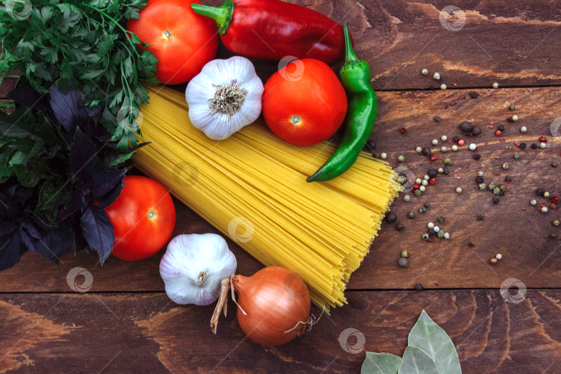 Скачать спагетти с овощами, луком, чесноком, болгарским перцем, перцем чили, помидорами и пучком петрушки вид сверху фотосток Ozero