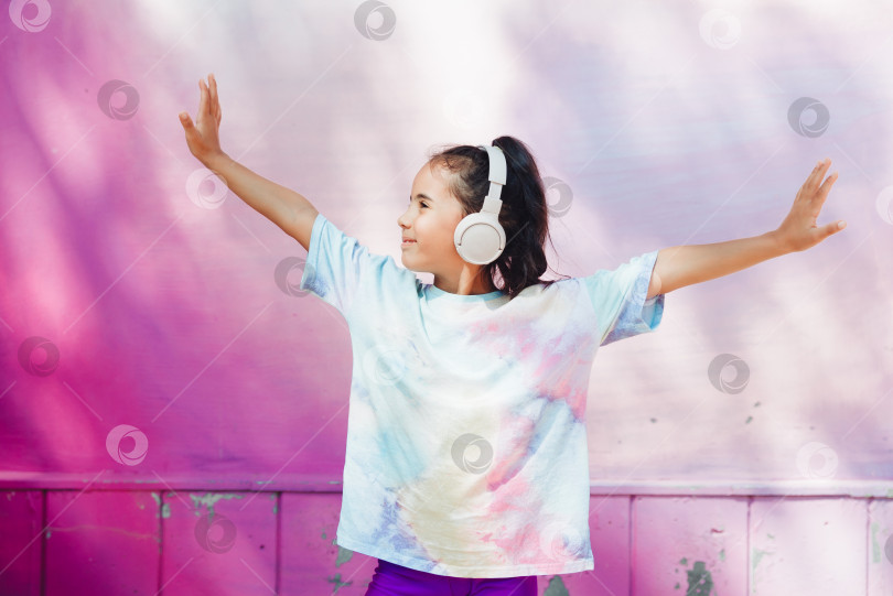 Скачать Счастливое детство. Счастливая маленькая девочка слушает музыку и танцует на улице. Маленький ребенок в наушниках. весенняя и осенняя мода. любимая музыка в наушниках. поколение z фотосток Ozero