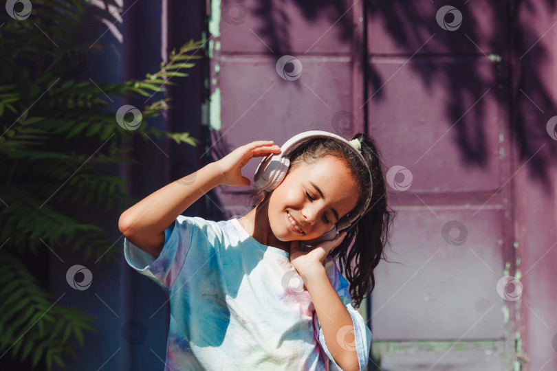 Скачать Счастливое детство. Счастливая маленькая девочка слушает музыку и танцует на улице. Маленький ребенок в наушниках. весенняя и осенняя мода. любимая музыка в наушниках. поколение z фотосток Ozero