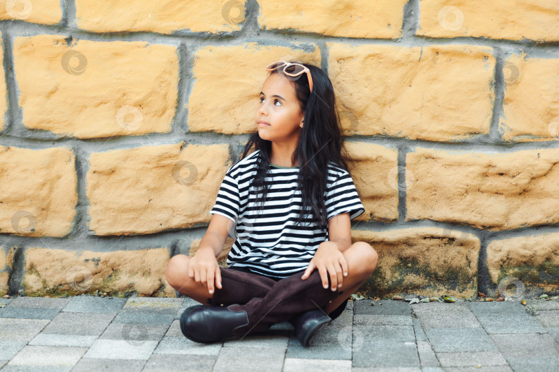 Скачать маленькая девочка в полосатой толстовке позирует на фоне кирпичной стены. детская осенняя мода. поколение z фотосток Ozero