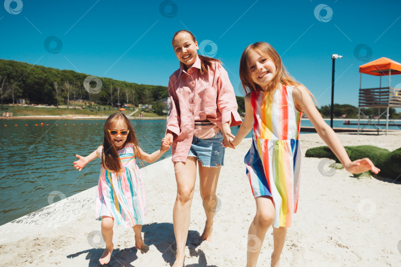 Скачать Мать и дети бегают и веселятся на пляже в дневное время. Концепция дружной семьи. фотосток Ozero