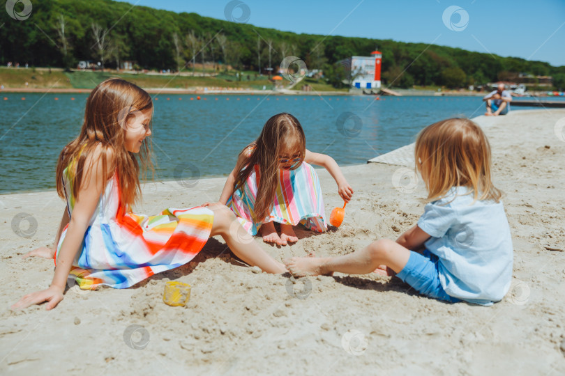 Скачать Счастливые дети летом играют на песчаном городском пляже. ребенок с синдромом Дауна фотосток Ozero