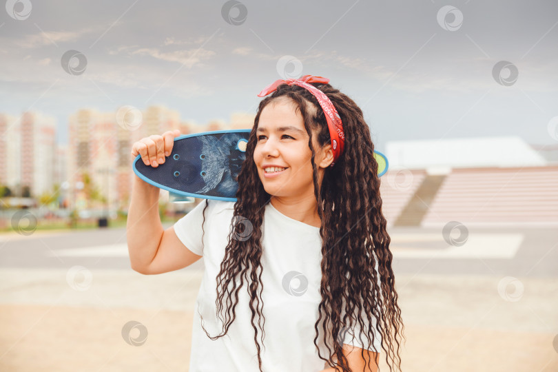 Скачать молодая женщина с дредами держит в руках скейтборд и слушает музыку.поколение z фотосток Ozero