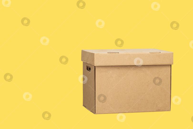 Скачать Картонная коробка, выделенная на желтом фоне фотосток Ozero