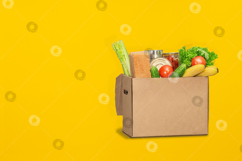 Скачать Коробка для пожертвований с едой на желтом фоне. Доставка еды из-за коронавируса. фотосток Ozero