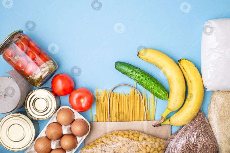 Скачать Доставка еды. Рис, гречка, макароны, консервы, сахар, помидоры, огурцы, бананы на синем фоне фотосток Ozero