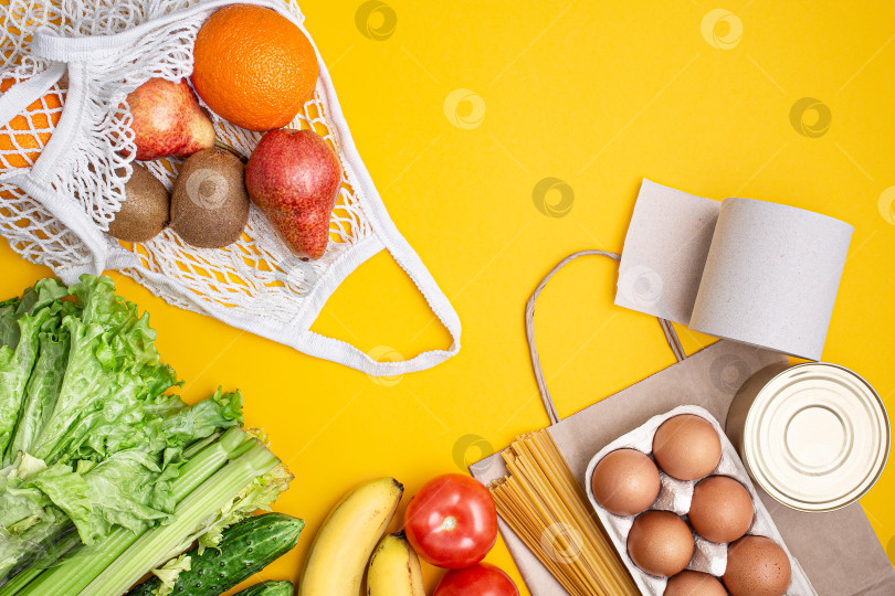 Скачать Бумажный пакет с продуктами, консервами, помидорами, огурцами, бананами на желтом фоне. фотосток Ozero