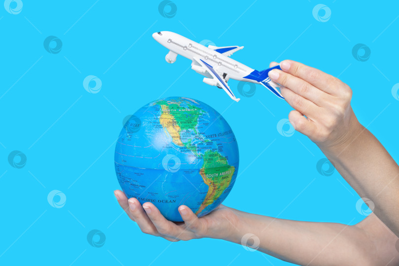 Скачать Концепция путешествия. Женские руки, держащие глобус и фигурку пассажирского самолета на синем фоне фотосток Ozero