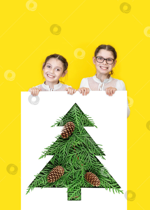 Скачать Счастливые маленькие дети выглядывают из пустого рождественского баннера на желтом фоне. фотосток Ozero