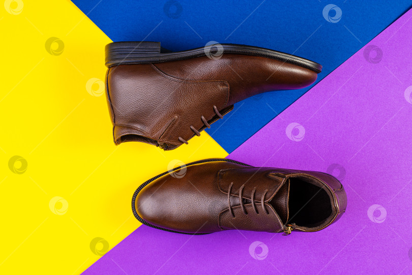 Скачать Пара коричневых кожаных ботинок на фоне цветной бумаги. фотосток Ozero
