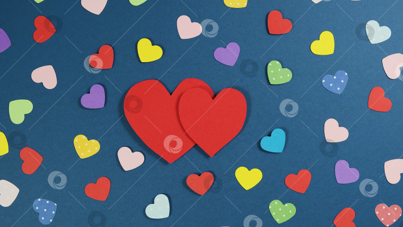 Скачать Праздничный абстрактный фон на день Святого Валентина с разноцветными бумажными сердечками. Вырезанное из бумаги сердечко на синем фоне фотосток Ozero