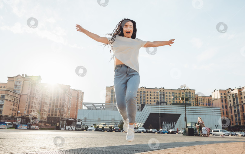Скачать Жизнерадостная женщина слушает музыку через наушники на улице в солнечный день. девушка в наушниках прыгает по улице. поколение z фотосток Ozero