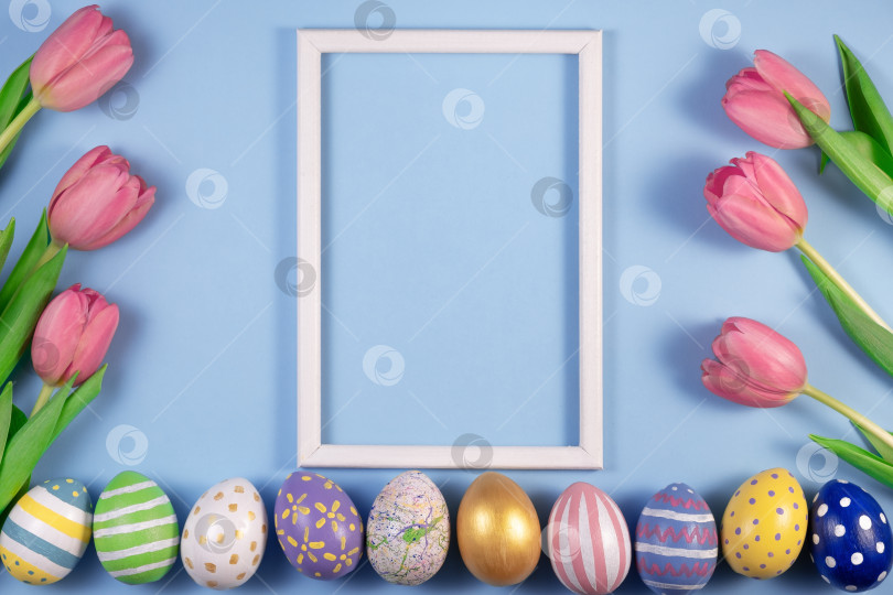 Скачать Цветы тюльпанов и пасхальные яйца в деревянной рамке на синем фоне. Открытка со счастливой Пасхой. фотосток Ozero