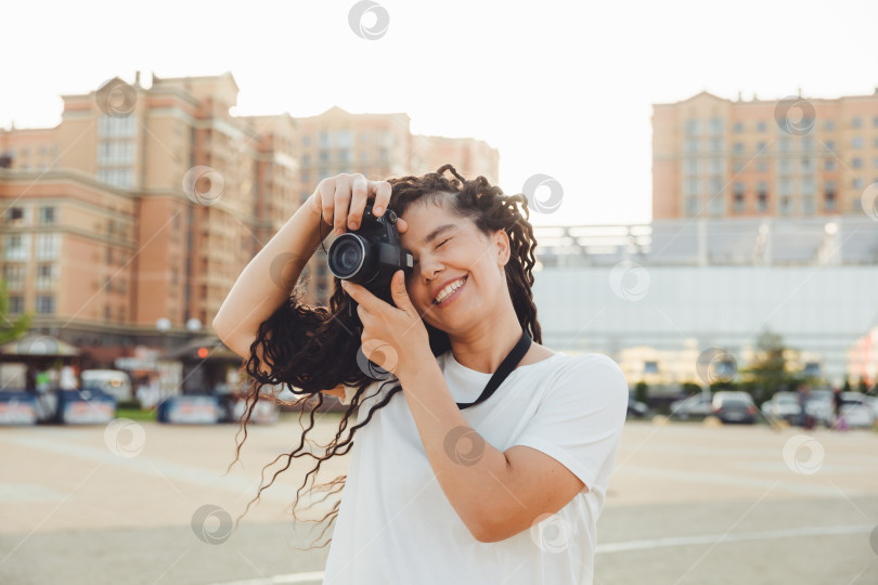 Скачать Молодой фотограф с профессиональной уличной камерой. Место для текста. девушка с дредами фотографирует городской пейзаж. фото. фотосток Ozero