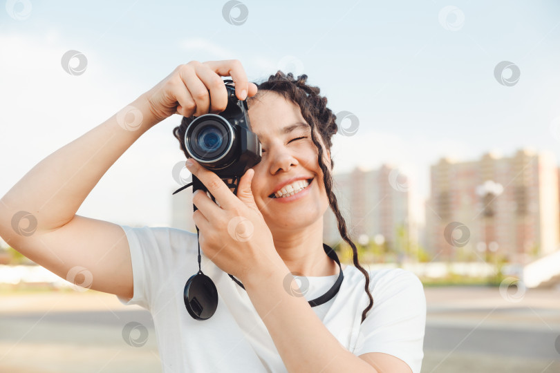 Скачать Молодой фотограф с профессиональной уличной камерой. Место для текста. девушка с дредами фотографирует городской пейзаж. фото. фотосток Ozero