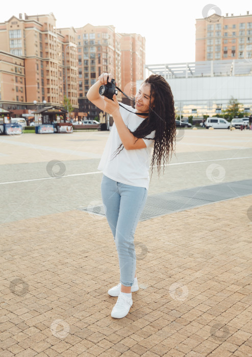 Скачать Молодой фотограф с профессиональной уличной камерой. Место для текста. девушка с дредами фотографирует городской пейзаж. фото. фотосток Ozero