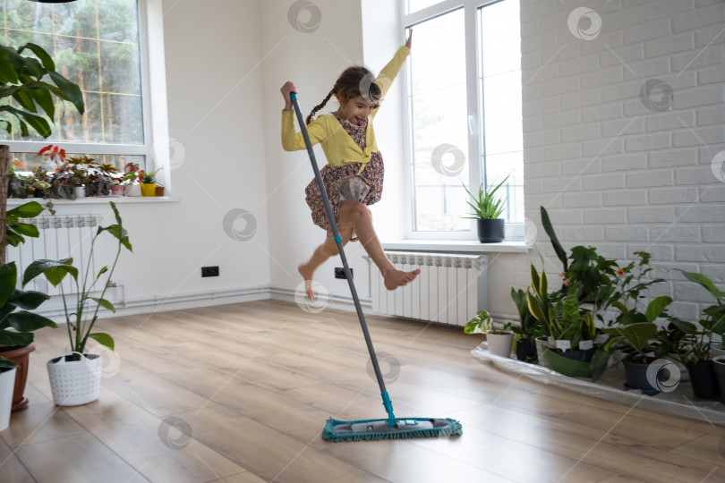 Скачать Девушка танцует со шваброй, чтобы вымыть пол в новом доме - генеральная уборка в пустой комнате, радость от переезда, помощь по хозяйству фотосток Ozero