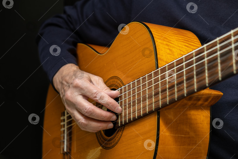 Скачать Гитарист, играющий на акустической гитаре на черном фоне, выборочный фокус фотосток Ozero