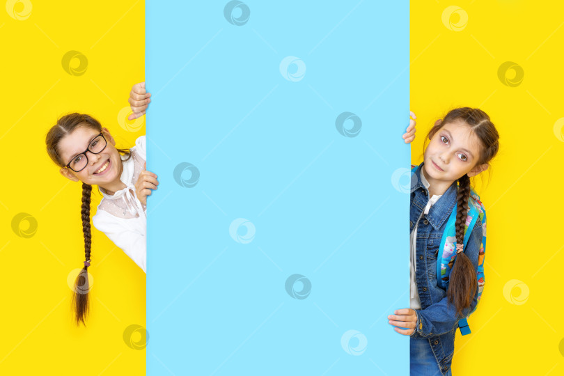 Скачать Девочки-сестры держат в руках голубой плакат empy и улыбаются. Копировальное пространство фотосток Ozero