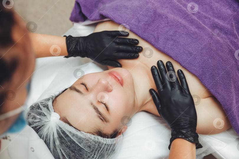 Скачать Руки косметолога делают ручной расслабляющий омолаживающий массаж лица молодой женщине в салоне красоты. Омолаживающий массаж лица фотосток Ozero