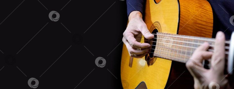 Скачать Гитарист, играющий на акустической гитаре на черном фоне, выборочный фокус. фотосток Ozero
