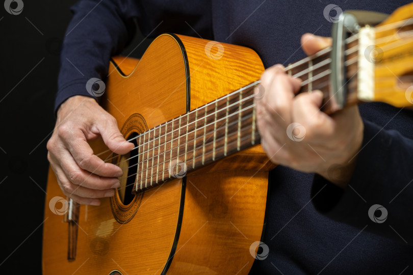 Скачать Гитарист, играющий на акустической гитаре на черном фоне, выборочный фокус. фотосток Ozero