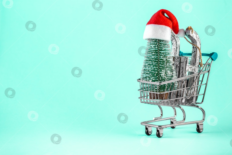 Скачать Корзина для покупок с рождественской елкой и шляпой Санта-Клауса на синем фоне. фотосток Ozero
