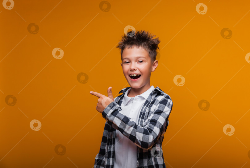 Скачать Счастливый эмоциональный мальчик удивлен, показывает что-то пальцем на синем фоне фотосток Ozero