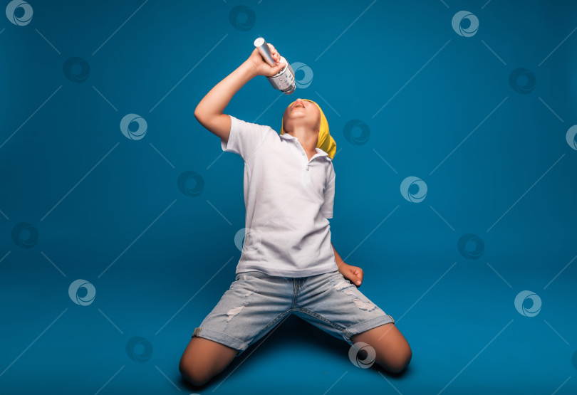Скачать мальчик поет в микрофон на синем фоне. Красивый мальчик в белой футболке и шортах стоит на синем фоне и эмоционально поет в микрофон. фотосток Ozero