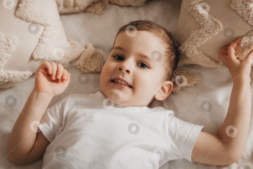 Скачать Милый маленький ребенок лежит на кровати, вид сверху. портрет мальчика в постели фотосток Ozero