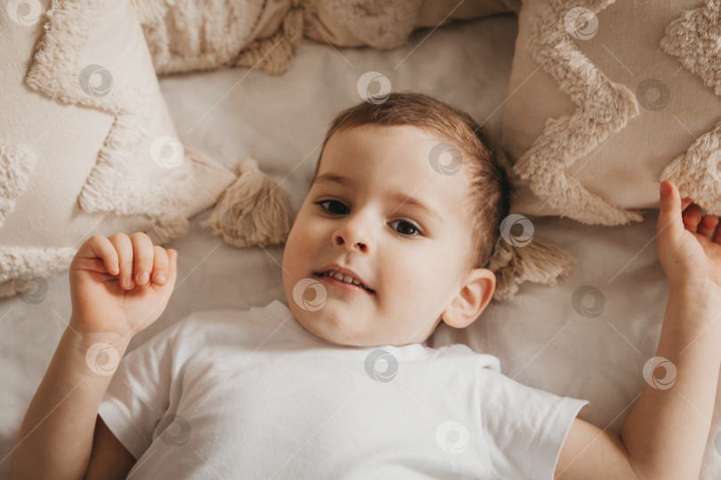 Скачать Милый маленький ребенок лежит на кровати, вид сверху. портрет мальчика в постели фотосток Ozero